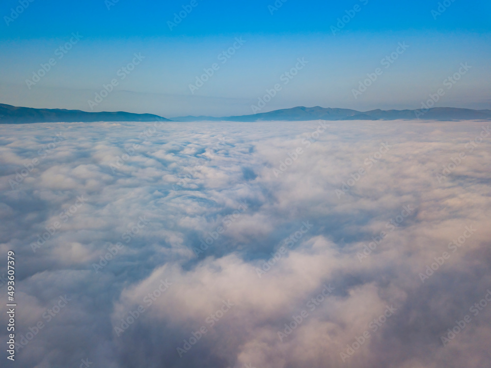 Flight over fog in Ukrainian Carpathians in summer. Mountains on the horizon. Aerial drone view.