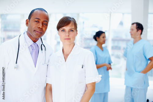 Doctors looking serious. Doctors standing together with nurses in background.