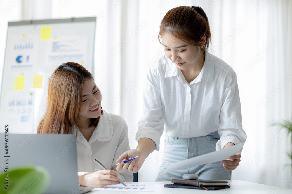 Two women sitting through white papers and talking, two business women discussing brainstorming and planning operations, form a partnership to form a startup company. Management of startup company. Two women sitting through white papers and talking, two business women discussing brainstorming and planning operations, form a partnership to form a startup company. Management of startup company.