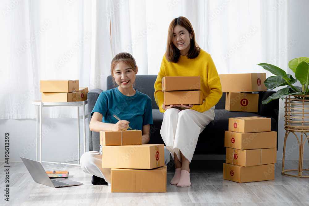 Two owners of an online store on the website are preparing parcels to send to customers following orders from the web page, they check the information and prepare for delivery to the customers. Two owners of an online store on the website are preparing parcels to send to customers following orders from the web page, they check the information and prepare for delivery to the customers.