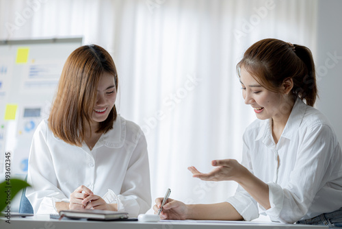 Two women sitting through white papers and talking, two business women discussing brainstorming and planning operations, form a partnership to form a startup company. Management of startup company.