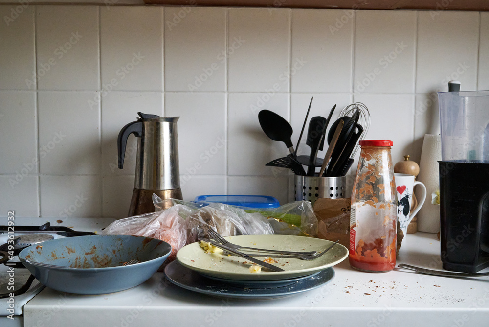Dirty plates, cutlery, kitchen utensils after cooking in a white kitchen