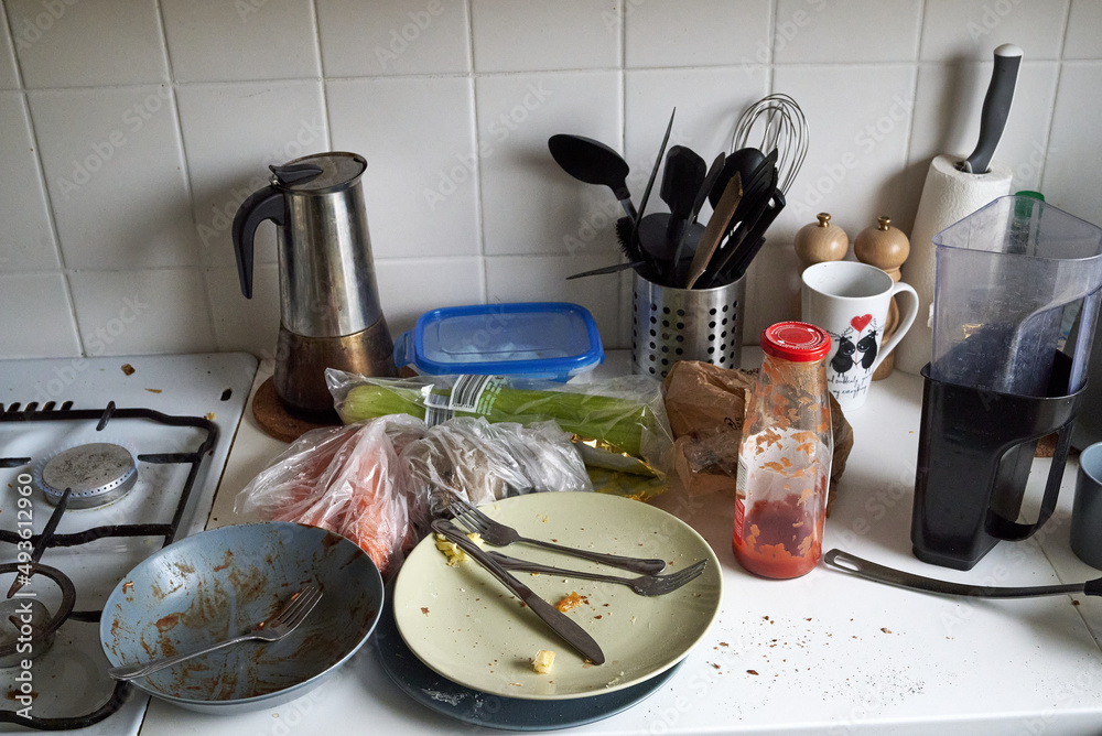 Dirty plates, cutlery, kitchen utensils after cooking in a white kitchen
