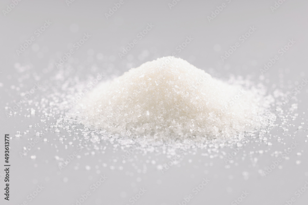 Sugar crystals pile on grey background, heap of sweet powder, sugar substitute Sugar crystals pile on grey background, heap of sweet powder, sugar substitute