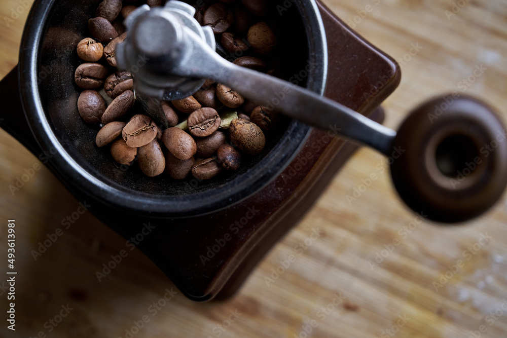 old wooden grinder and black coffee beans in daylight