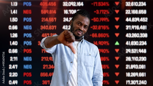 Unhappy man showing thumbs down on stock market background, bad investment, loss