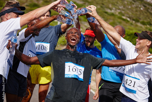 That was an amazing race. Shot of a group of young men pouring water over their friend after running a marathon.