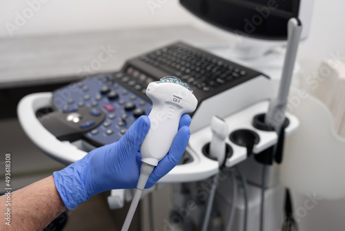 Probe for ultrasound diagnostics close-up. The doctor holds in his hands a transducer with a gel for ultrasound diagnostics of internal organs. Modern ultrasonic machine. Elastography and sonography. photo