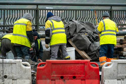 Employees of the road service in special yellow vests perform work on the repair of the roadway. Restoration of the deformation seam of the automobile bridge.