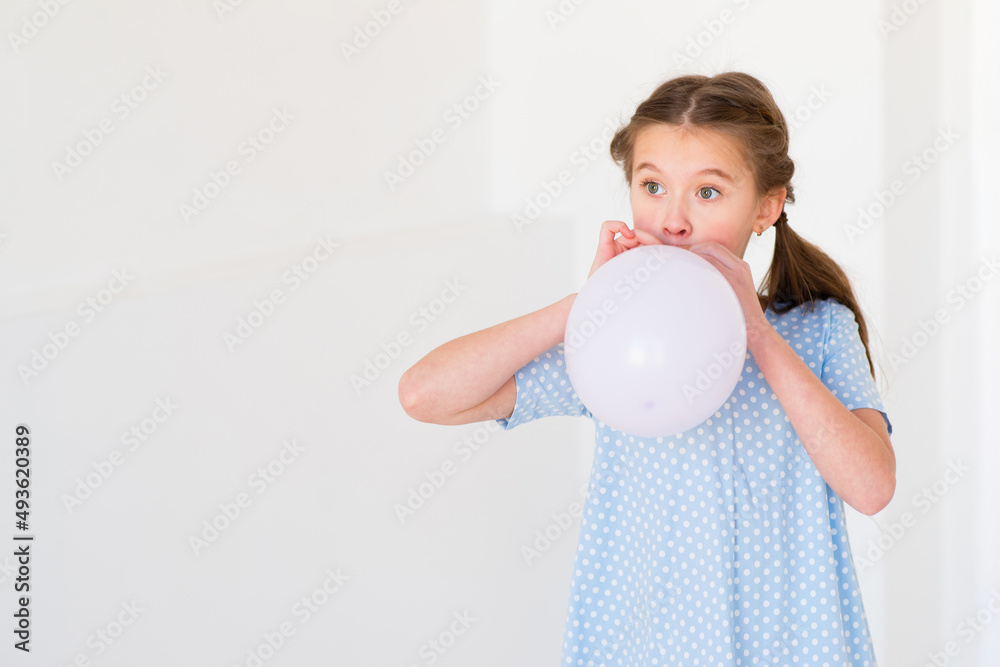 child little girl in a blue dress inflates a balloon
child little girl in a blue dress inflates a balloon