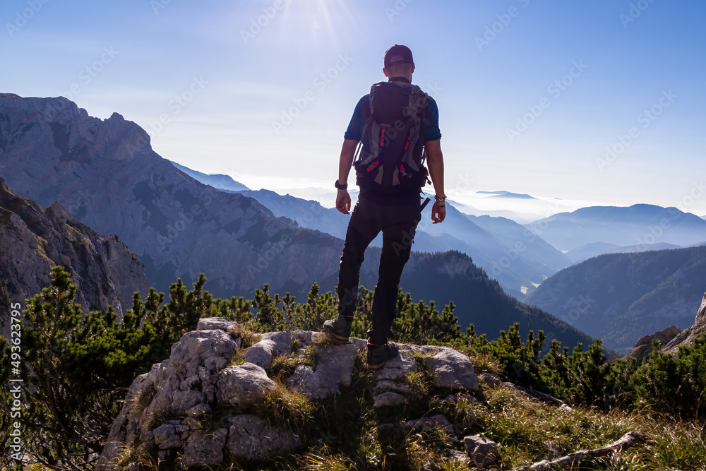 Man with backpack hiking in the scenic region of the Hochschwab mountain in Styria, Austria, Europe. Mystical blue hills in the valley in Austrian Alps. Hike concept. Freedom, fresh air. Sunny summer