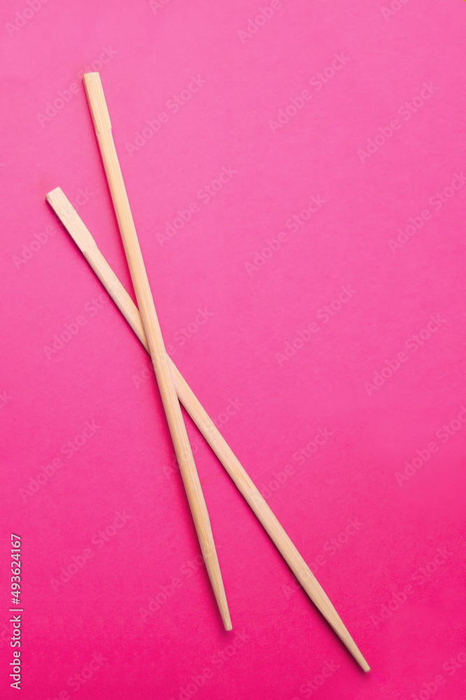 Wooden pairs of chopsticks on pink background Wooden pairs of chopsticks on pink background
