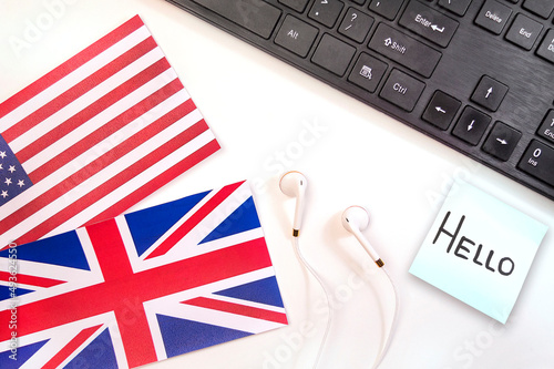 White headphones with black keyboard on the background of the flag of Britain and the USA with a sticker saying hello