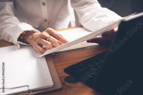 Business woman reviewing data in financial charts and graphs on wooden desk in office and business working, tax, accounting, statistics and analytic research concept