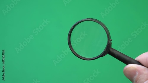 Hand of man holding magnifying glass to examine something, bring it closer. Chroma key