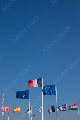 ensemble de drapeaux de l'union européenne. Au centre et au premier plan, le drapeau de l'Europe et le drapeau français. Un beau ciel bleu en arrière plan et un large emplacement prévu pour le texte