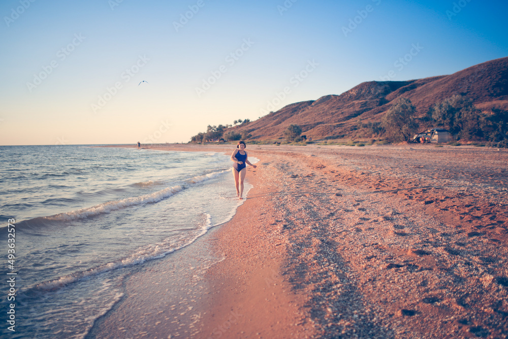 Cute european child teen girl run along the beach by the sea, happy childhood and freedom. Plus size kid, overweight and sports by the sea