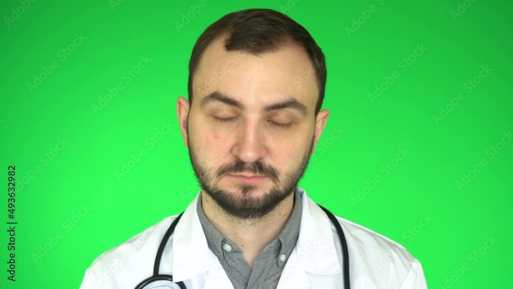 Medical doctor man looking at camera waving head yes positive answer approval, green background,