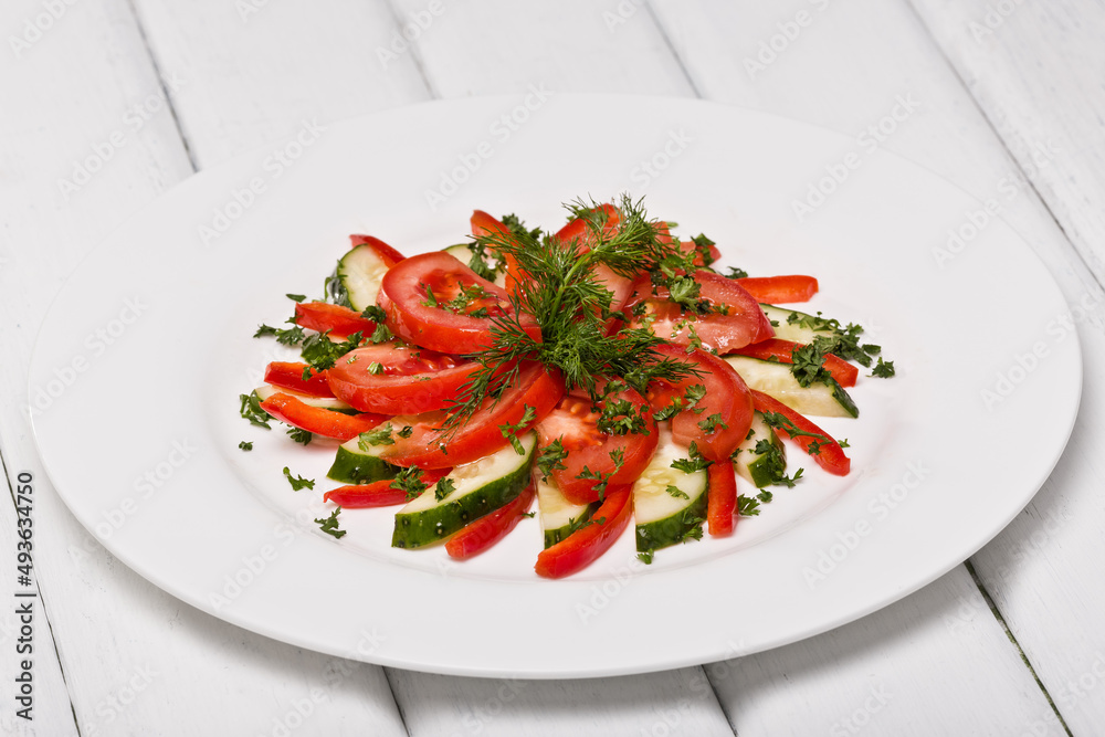 Salad in a plate, tomatoes and cucumbers. Photo of food on a white background Salad in a plate, tomatoes and cucumbers. Photo of food on a white background
