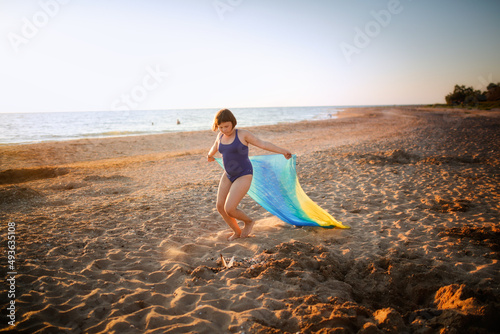 Cute european child teen girl run along the beach by the sea, happy childhood and freedom. Plus size kid, overweight and sports by the sea