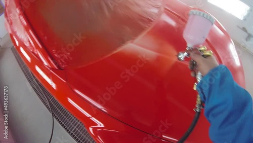 Auto painter spraying paint of the car in special booth. Painting vehicle parts at car service workshop.