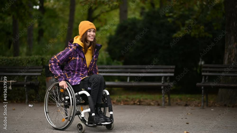 Woman with disability who uses a wheelchair using a smartphone while in the park