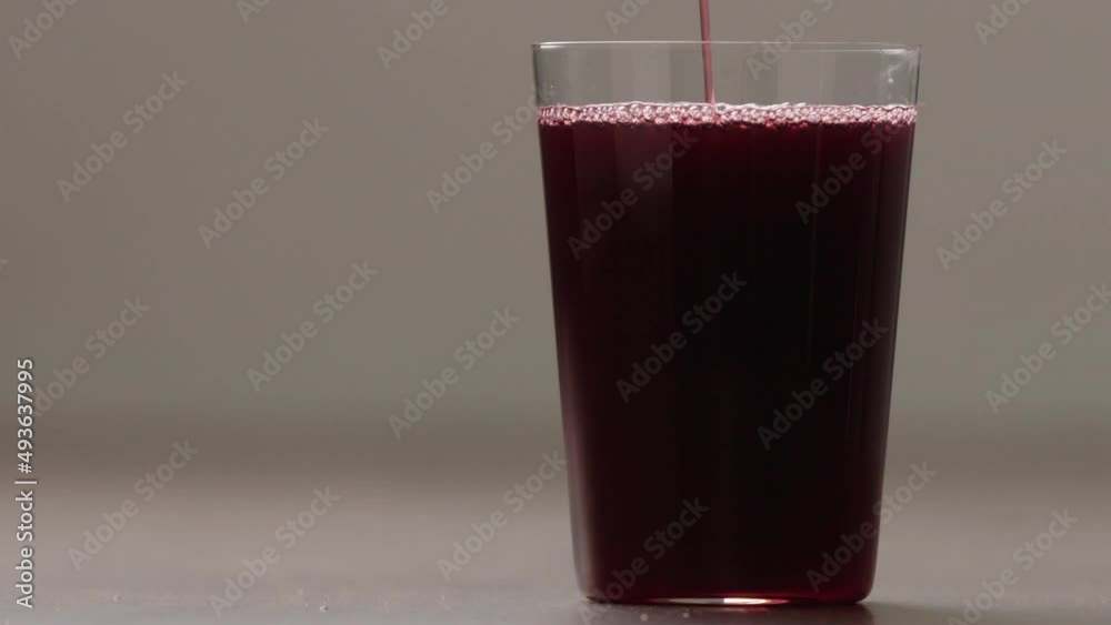 Slow motion pour berry juice in tumbler glass closeup Slow motion pour berry juice in tumbler glass closeup