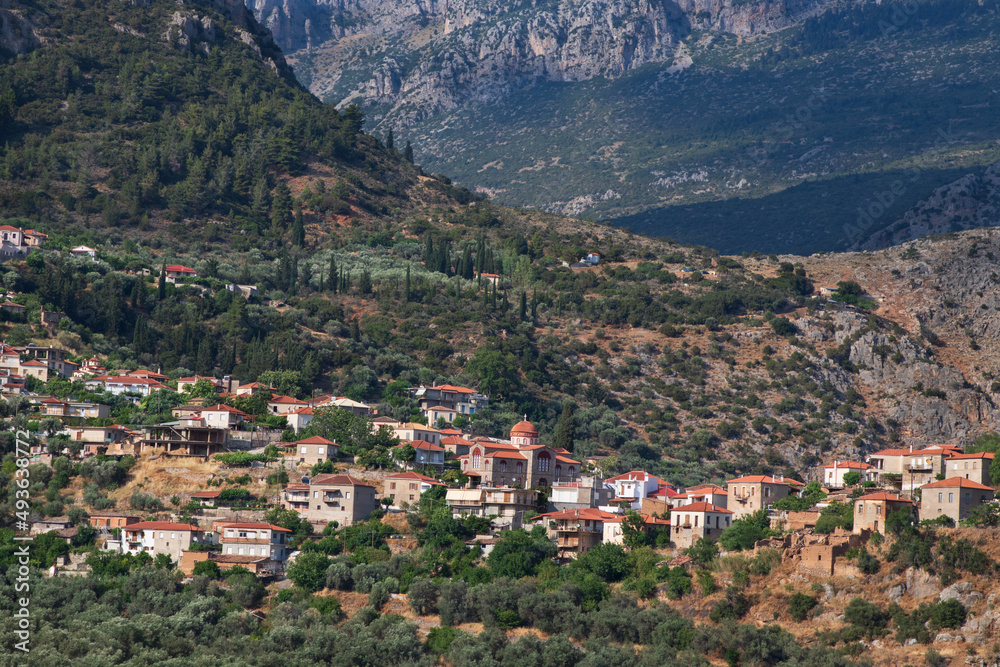 Greek village in the mountains with church and beutiful green trees, olive trees and cypresses in summer, Greece