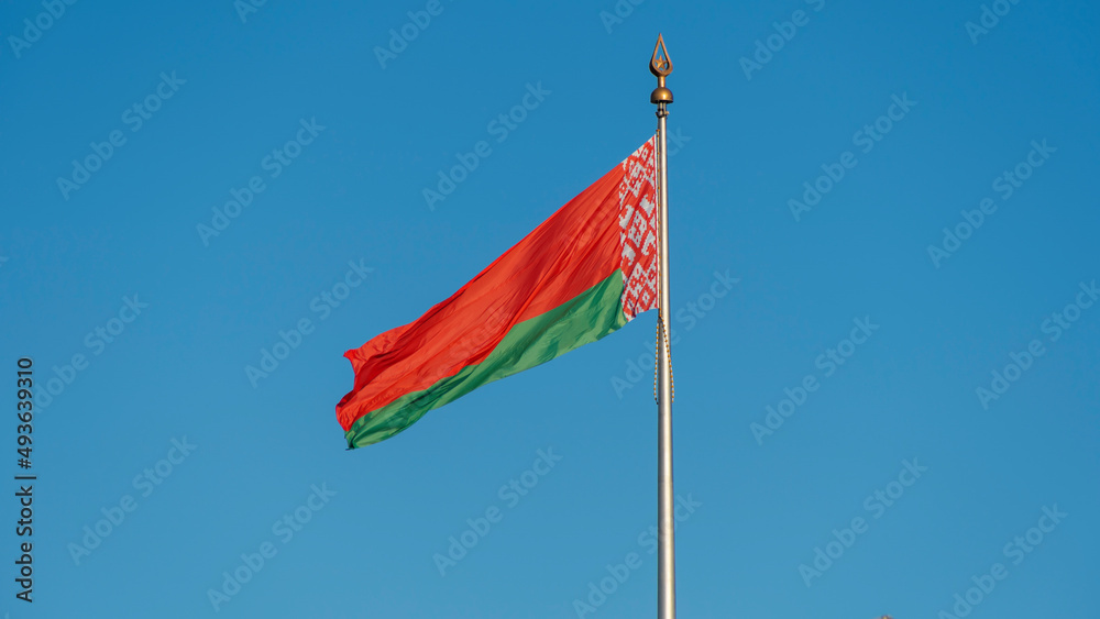 State flags of the Republic of Belarus are waving in the wind on blue sky background. Space for text. State flags of the Republic of Belarus are waving in the wind on blue sky background. Space for text.