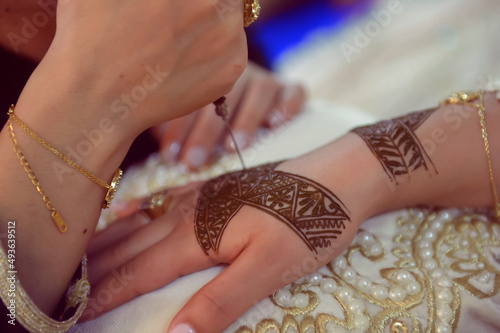 Artist applying henna tattoo on women hands. Mehndi is traditional moroccan decorative art. Close-up, top view.