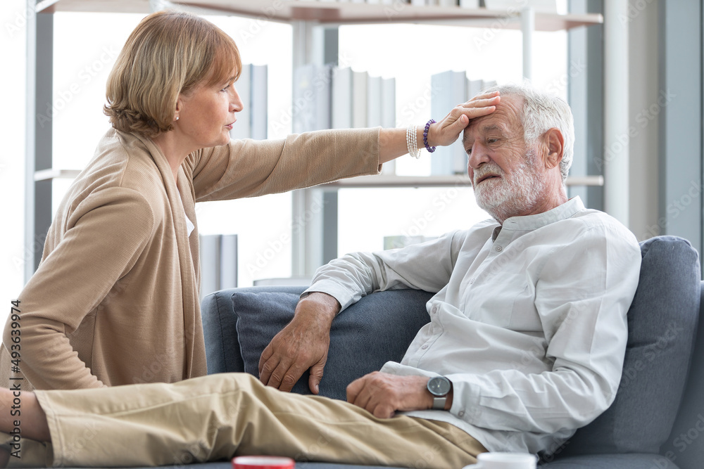 Fototapeta premium senior woman touching forehead her husband on sofa