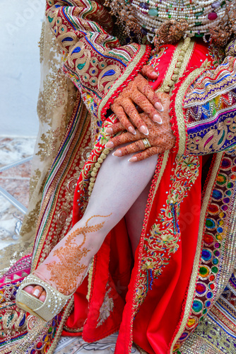 The leg of a Moroccan bride tattooed with henna with the Moroccan caftan