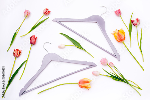 Clothes hangers with tulips on white background. Flat lay, top view photo