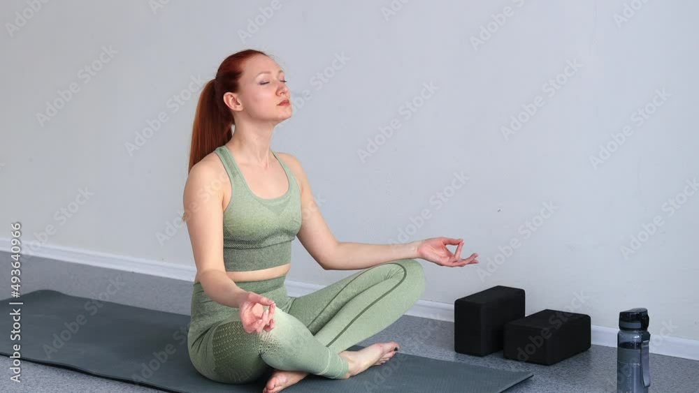 a young woman sits on a sports mat doing yoga a young woman sits on a sports mat doing yoga