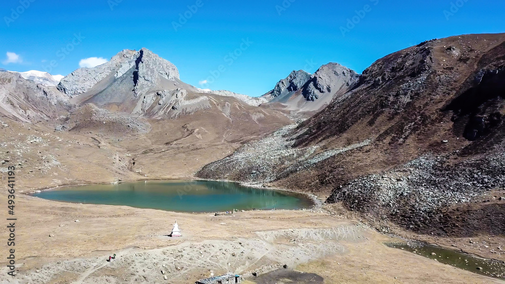A view on the Ice Lake, along Annapurna Circuit Trek detour, Himalayas, Nepal, surrounded by high mountains. Stupa in front of the lake. Snowy mountain peaks in the back. High altitude lake.