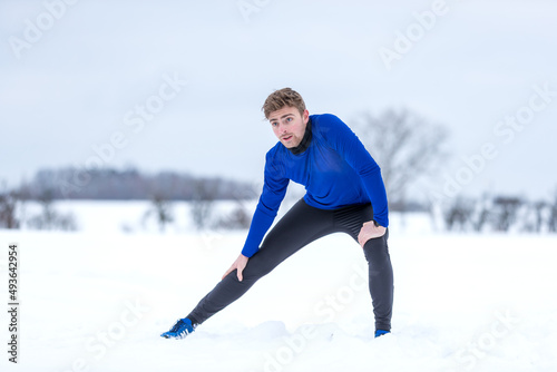 Winterlaufübung - Sportler beim Streching in einer weißen verschneiten Landschaft