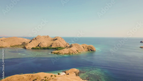 A drone shot of two bigger paradise islands in Komodo National Park, Flores, Indonesia. The islands have scarcely any trees and bushes. Dry land. Idyllic white sand beaches. Island hoping