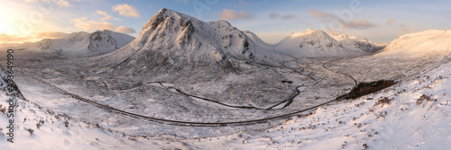 Huge panorama showing incredible view of iconic Glencoe mountains covered in snow with golden morning light. Buachaille, Scottish Highlands, UK. photo