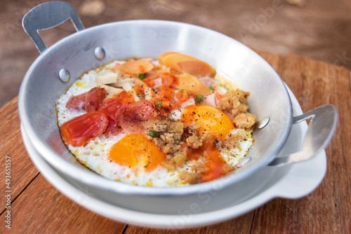 Eggs are cooked in a little pan served in, and topped with sweet sausage and pork stick. Pan Eggs or "Kai Grata” is a breakfast that is popular in Thailand.