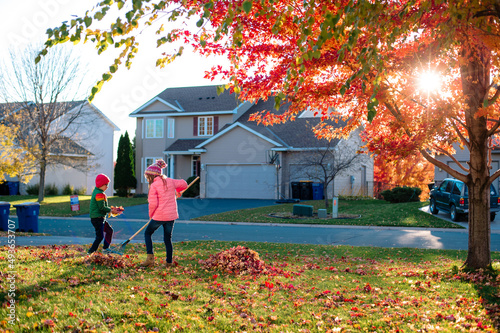 Valokuva Two children rake leaves in front of their house