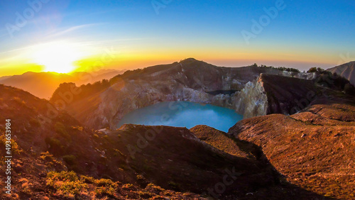 Sunrise over the Kelimutu volcanic crater lakes in Moni, Flores, Indonesia. Skyline is bursting with orange. Turquoise color of the lake. Golden hour colours the surroundings. Beauty of the nature © Chris