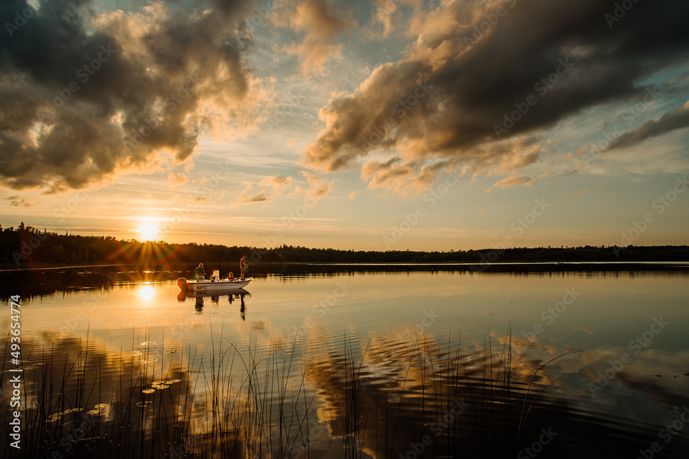 A grandfather, father, and daughter fish on a lake in northern Minnesota at sunset