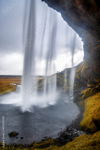 Seljalandsfoss waterfall in southern Iceland. Seen from a cave behind. Unidentifiable photographers shoot from the other direction.