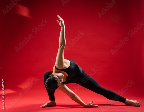 beautiful static poses. pilates on red background Woman in black sportswear. gymnastic poses