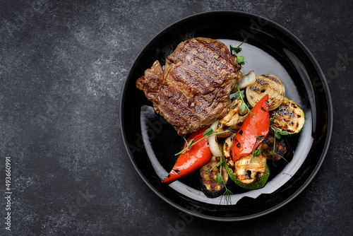 Meat steak with grilled vegetables on a black plate