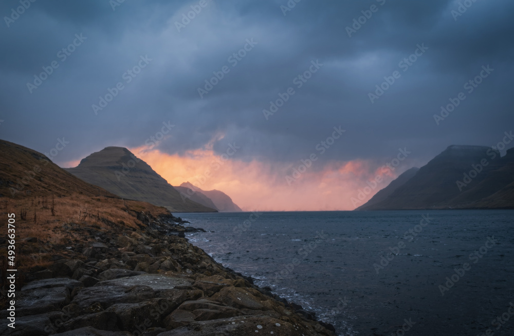 Faroe Islands, Kalsoy island near Husar village in sunset light durig twilight with pink sky and cliffs. November 2021