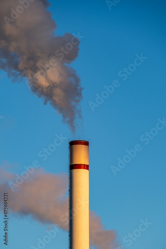 a chimney with dark smoke against a blue sky 