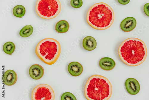 Fruity pattern of kiwi and grapefruit slices on the white background. Top view. Minimal colourful trend style