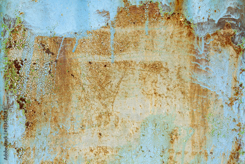Brown beige abstract background with orange blue hues. A rust-eaten textured sheet of metal with remnants of paint marks.