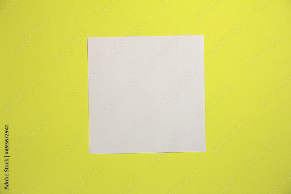 White square sheet of paper. On a yellow background. Top view. White square sheet of paper. On a yellow background. Top view.